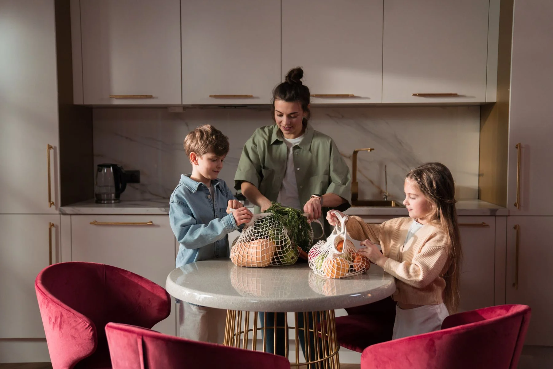 A mother and children unpacking groceries at the kitchen table